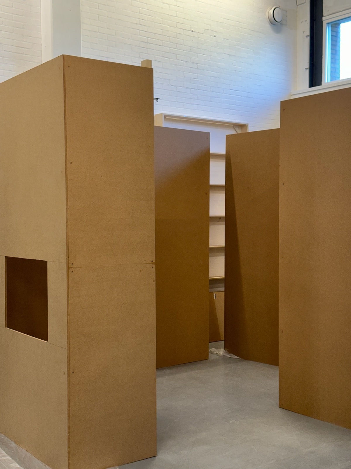 Tall wooden panels that form small rooms in a white hall